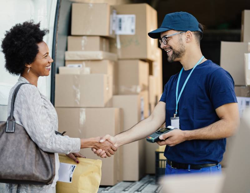 a man talking to a woman about package delivery and shaking hands